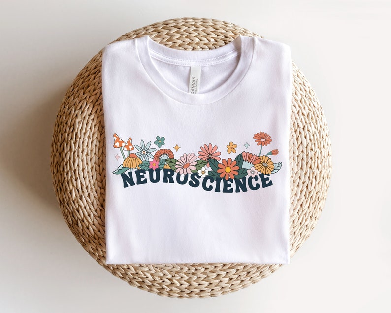 May include: White t-shirt featuring a floral design and the word "NEUROSCIENCE" in black lettering.