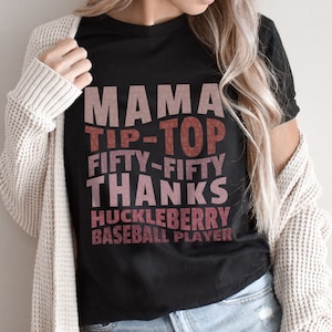 May include: Black t-shirt with a pink and red graphic that says "Mama Tip-Top Fifty-Fifty Thanks Huckleberry Baseball Player"