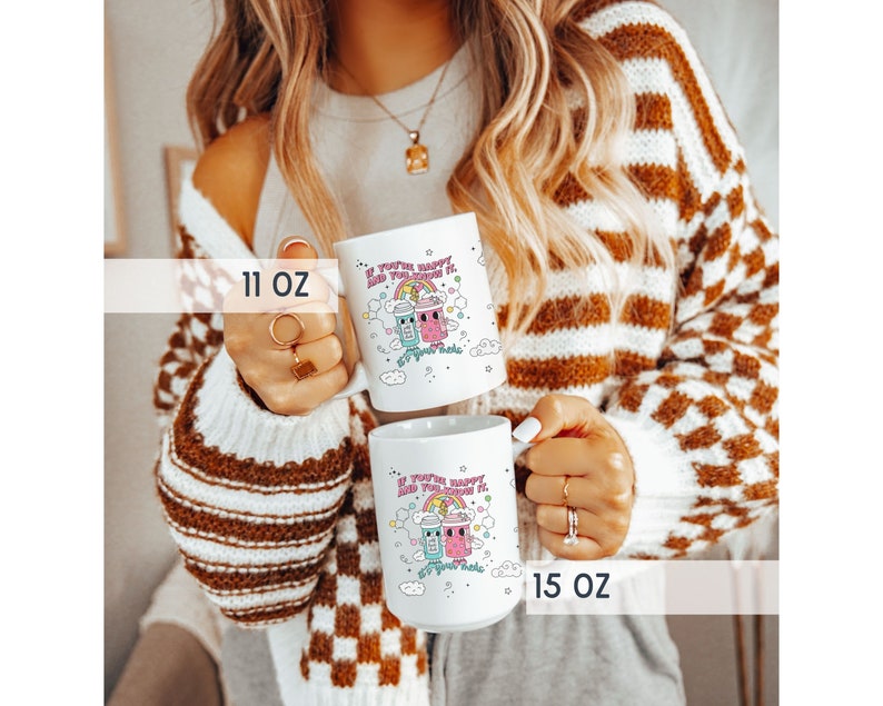 May include: Two white ceramic mugs with a colourful cartoon design. The mugs feature a rainbow, clouds, and two cartoon characters holding drinks. The text on the mugs reads "If you're happy and you know it, sip your tea". The mugs are available in 11 oz and 15 oz sizes.
