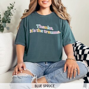 May include: A teal blue t-shirt with the text "Thanks, it's the trauma." in colorful letters.