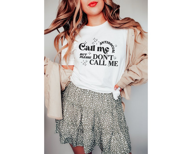 Puede incluir: Camiseta blanca con texto negro que dice "Call me antisocial but please don't call me". El texto est&aacute; rodeado de estrellas.