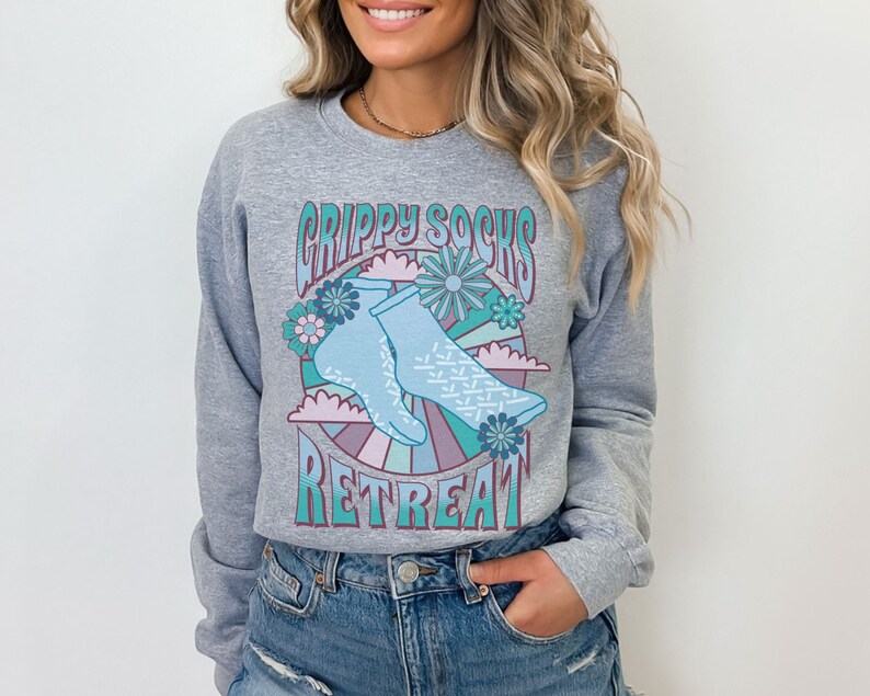 May include: Gray sweatshirt with a retro-style graphic of blue grippy socks with a floral design and the text "Grippy Socks Retreat".