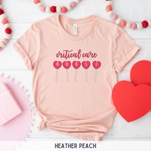 Pu&ograve; includere: Una maglietta rosa con la scritta "critical care nurse" e cinque lecca-lecca a forma di cuore rosso con le lettere "NURSE" su di esse.