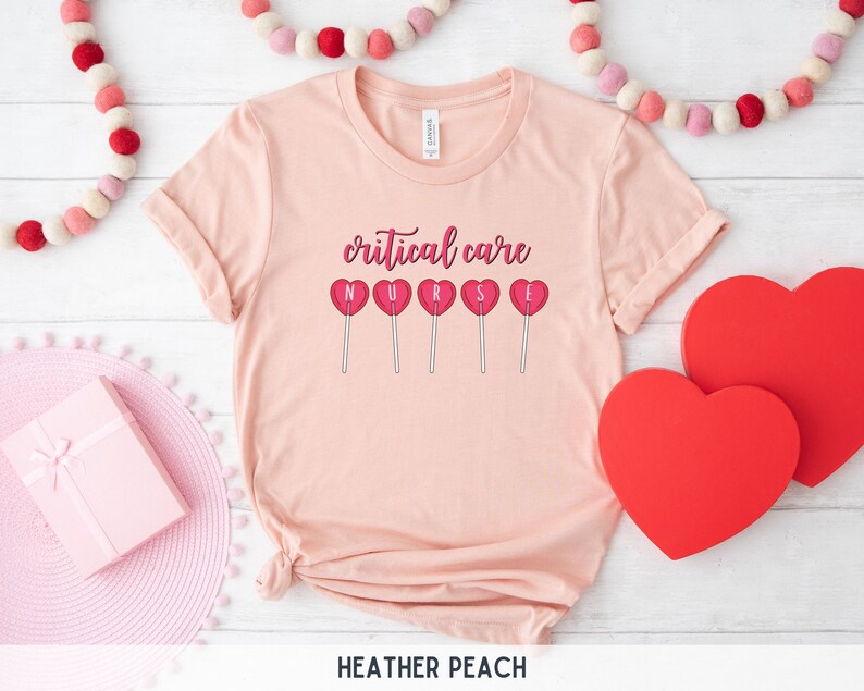 Pu&ograve; includere: Una maglietta rosa con la scritta "critical care nurse" e cinque lecca-lecca a forma di cuore rosso con le lettere "NURSE" su di esse.