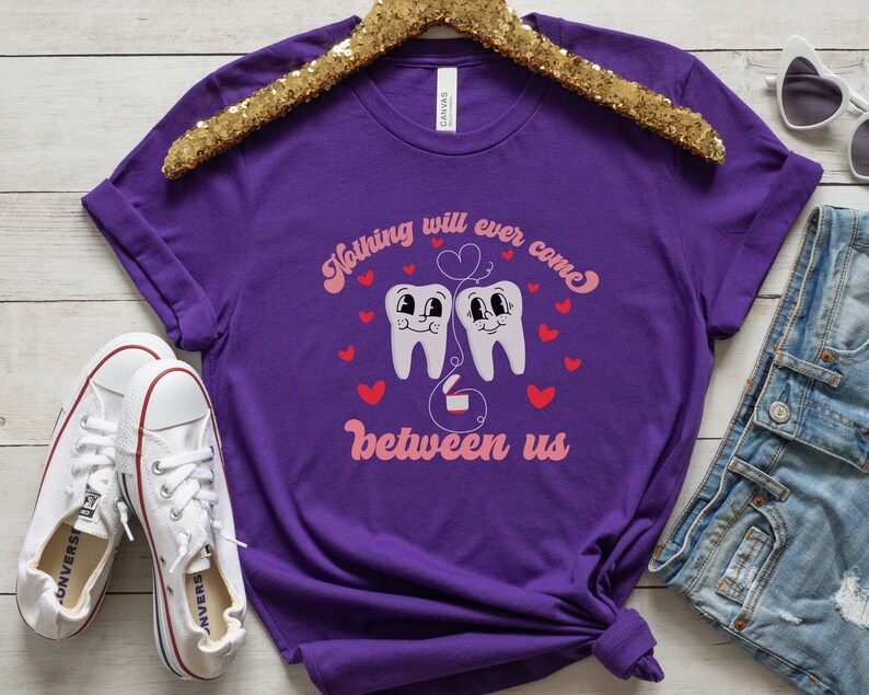 Puede incluir: Camiseta morada con un gr&aacute;fico de dos dientes de dibujos animados con un coraz&oacute;n rosa y el texto "Nada nos separar&aacute; jam&aacute;s".