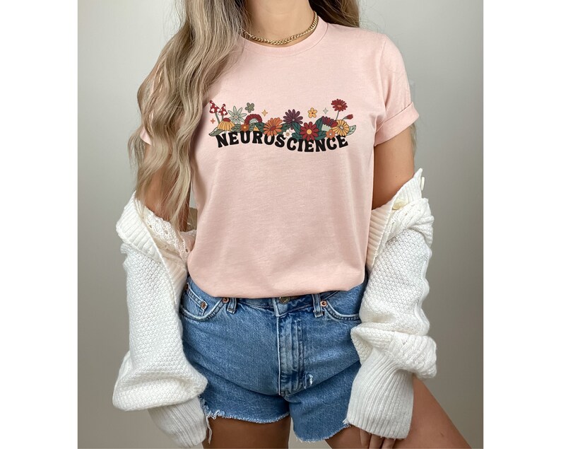 May include: A pink t-shirt with a floral design and the text "NEUROSCIENCE" in black letters.