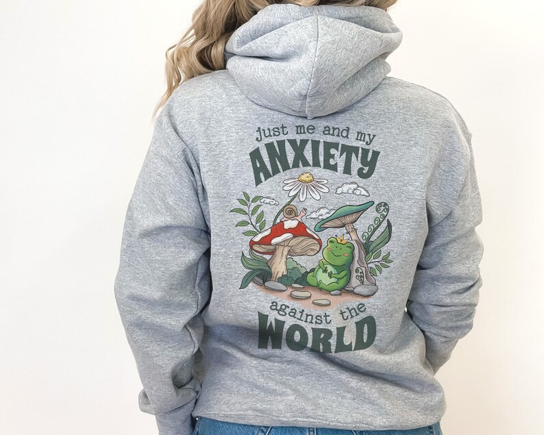 May include: Gray hooded sweatshirt with a green, red, and white graphic of a frog sitting on a mushroom with the text "Just me and my anxiety against the world".