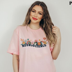 May include: A pink t-shirt with a floral design and the text "NEUROSCIENCE" in black.