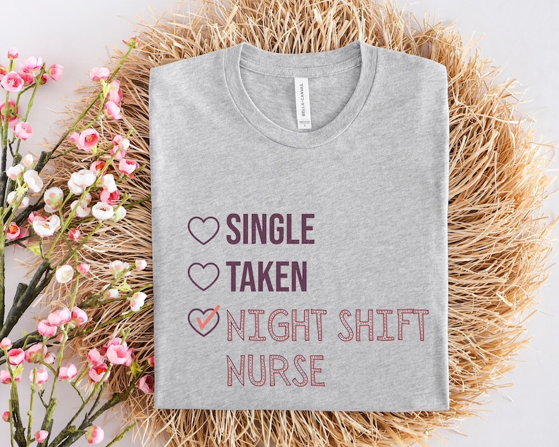 May include: Gray t-shirt with a pink heart graphic and the text "Single, Taken, Night Shift Nurse" in purple.