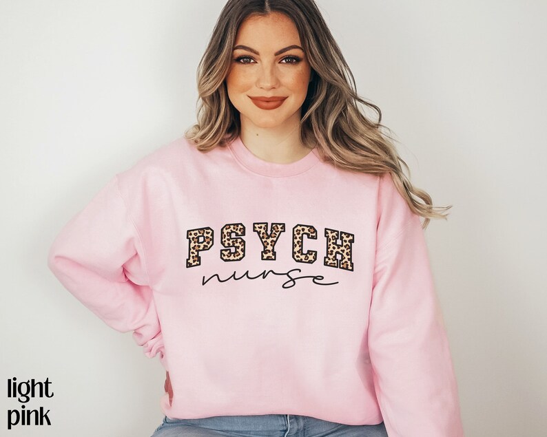 May include: Light pink sweatshirt with the text "PSYCH nurse" in black script and leopard print lettering. The words "light pink" are in the bottom left corner.