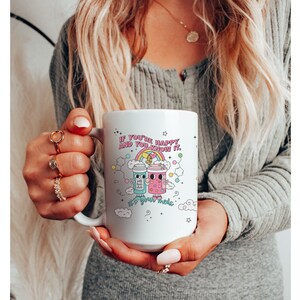 May include: White ceramic mug with a colourful illustration of two cartoon coffee cups with the text "If you're happy and you know it, it's your meds."