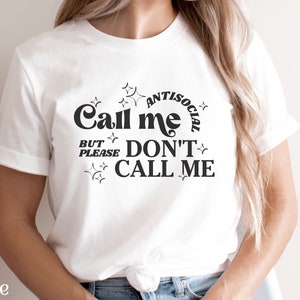 Puede incluir: Camiseta blanca con texto negro que dice "Call me antisocial but please don't call me". El texto est&aacute; rodeado de estrellas.