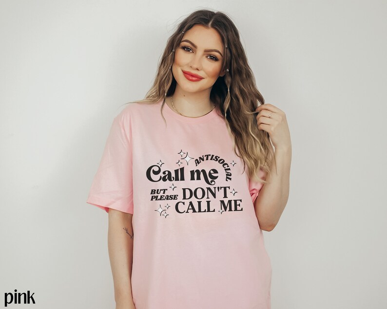 Puede incluir: Camiseta rosa con un gr&aacute;fico negro que dice "Call me Antisocial But Please Don't Call Me".
