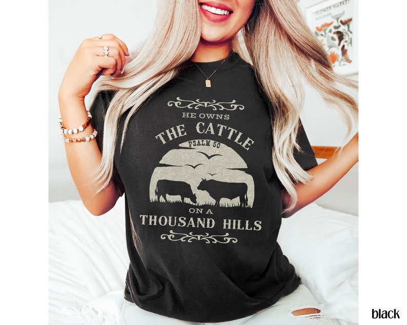 May include: Black t-shirt with a white graphic design featuring two cows and the text "He owns the cattle on a thousand hills, Psalm 50".