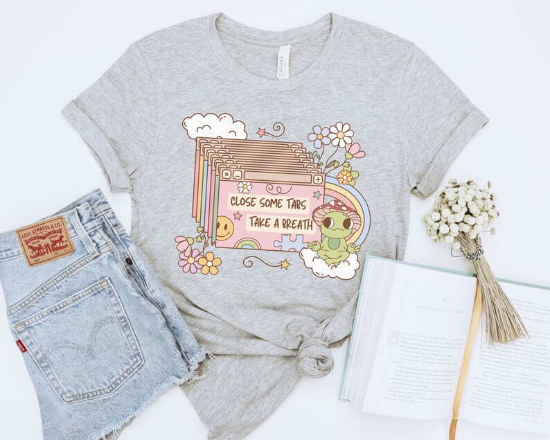 May include: Gray t-shirt with a cartoon frog and the text "Close some tabs take a breath". The design features a stack of browser tabs with a rainbow and a smiley face.