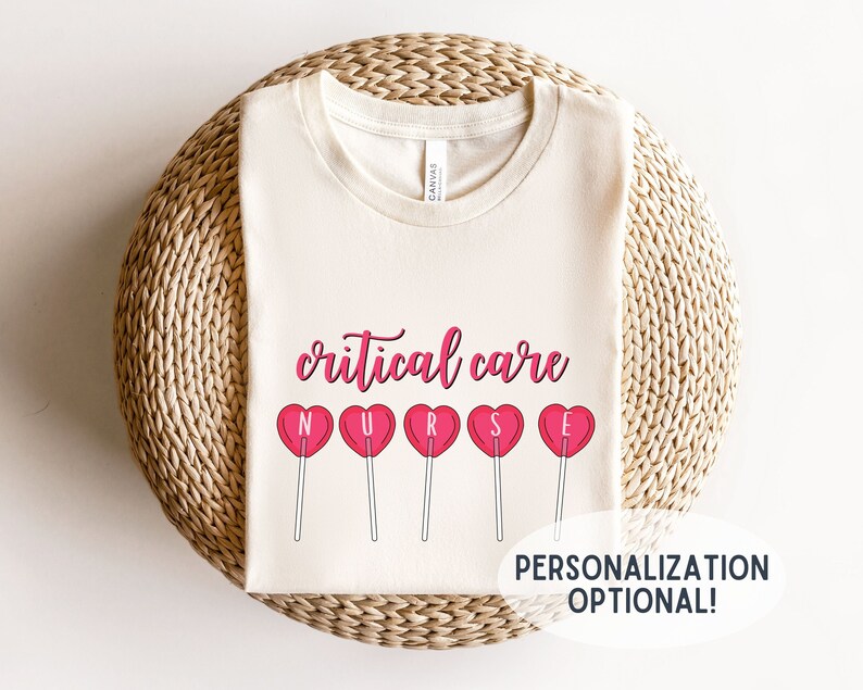 Pu&ograve; includere: Una maglietta bianca con il testo "critical care" e una fila di lecca-lecca a forma di cuore rosa che compongono la parola "NURSE". Il testo "PERSONALIZATION OPTIONAL!" &egrave; in fondo alla maglietta.