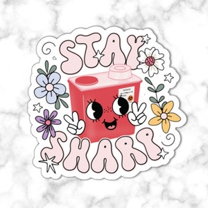 Puede incluir: Una taza de cerámica blanca con asa negra y el texto "But First, Coffee" en negrita negra. La taza está sobre un fondo borroso, sugiriendo un ambiente acogedor. La taza mide aproximadamente 10 cm de altura.