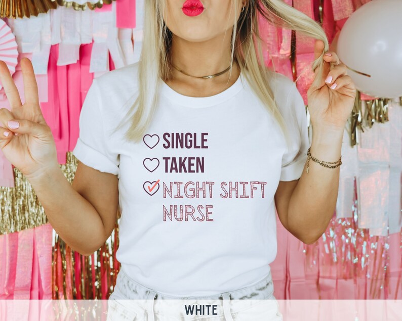 May include: White t-shirt with a pink heart design and the text "SINGLE TAKEN NIGHT SHIFT NURSE" with a checkmark next to "NIGHT SHIFT NURSE".