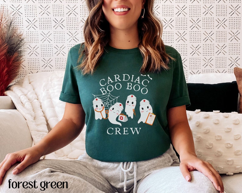 May include: A forest green t-shirt with the text "Cardiac Boo Boo Crew" and a graphic of three ghosts wearing nurse hats.