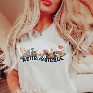 May include: A grey t-shirt with a floral design and the text "NEUROSCIENCE" in black letters.