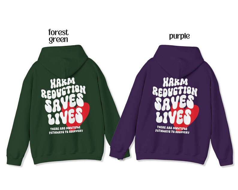 Peut inclure: Deux sweats &agrave; capuche, un vert for&ecirc;t et un violet, avec le texte "HARM REDUCTION SAVES LIVES" en blanc et un c&oelig;ur rouge. Le texte "THERE ARE MULTIPLE PATHWAYS TO RECOVERY" est en dessous. Ils ont tous les deux des capuches et des manches longues.
