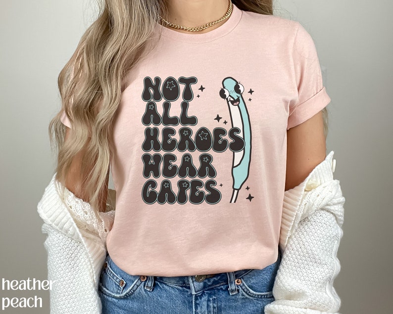 May include: Pink t-shirt with a graphic of a blue thermometer with a face and the text "Not All Heroes Wear Capes".