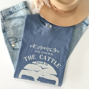 May include: A blue t-shirt with a white graphic that says "He owns the cattle Psalm 50".