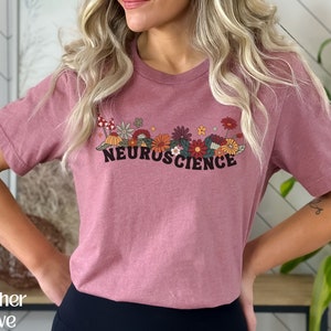 May include: A heather mauve t-shirt with a floral design and the text "NEUROSCIENCE" printed on the front.