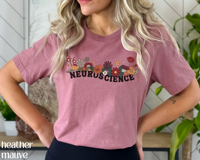 May include: A heather mauve t-shirt with a floral design and the text "NEUROSCIENCE" printed on the front.