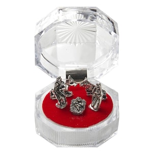 May include: A clear plastic box with a red velvet interior, containing a silver nativity set. The set includes figures of Mary, Joseph, the baby Jesus, and two animals.