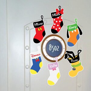 May include: Seven Christmas stockings with different Disney characters on them. The stockings are red, orange, blue, white, pink, and black. The characters are Mickey Mouse, Minnie Mouse, Donald Duck, Goofy, Pluto, and Daisy Duck. The stockings are hanging on a white door with a round porthole with the number 8502.