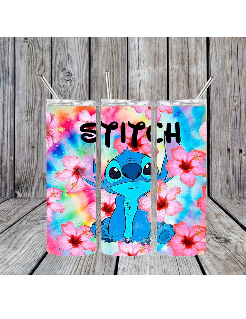 Peut inclure: Trois gobelets en acier inoxydable avec un personnage bleu Stitch et des fleurs d'hibiscus roses sur un fond tie-dye. Les gobelets ont des couvercles et des pailles. Le texte "Stitch" est imprim&eacute; sur les gobelets.
