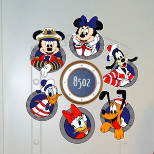 May include: A white door with six round porthole stickers featuring various Disney characters in nautical outfits. The portholes have a blue background with a white border. The centre porthole has a blue background with a white border and the number 8502.