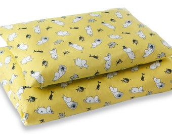 May include: A yellow duvet cover and pillowcase set with a white and black print of a cartoon character. The character is a white hippopotamus with black eyes and a black nose. The character is wearing a black hat and a black bow tie. The character is surrounded by black and white geometric shapes.