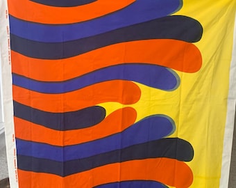 May include: A large fabric flag with a yellow background and a design of blue, red, and black wavy lines. The lines are curved and create a flowing pattern.