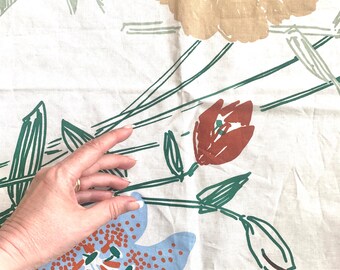 May include: Floral fabric with a cream background. The design features large flowers in shades of tan, orange, red, and blue, with green stems and leaves. The fabric has a vintage, hand-painted aesthetic.