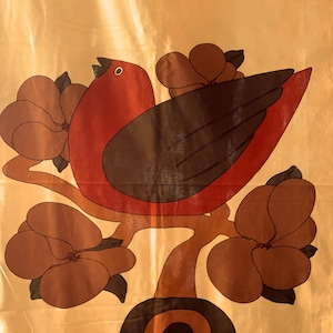 Peut inclure: Textile décoratif avec un motif d'oiseau stylisé sur une branche avec de grandes fleurs marron. L'oiseau est rouge et marron, avec un œil blanc. Le fond est de couleur or clair, avec un motif répétitif d'arche marron.