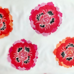 May include: White fabric with a repeating pattern of pink, red, and orange stylized flowers with black and white details.