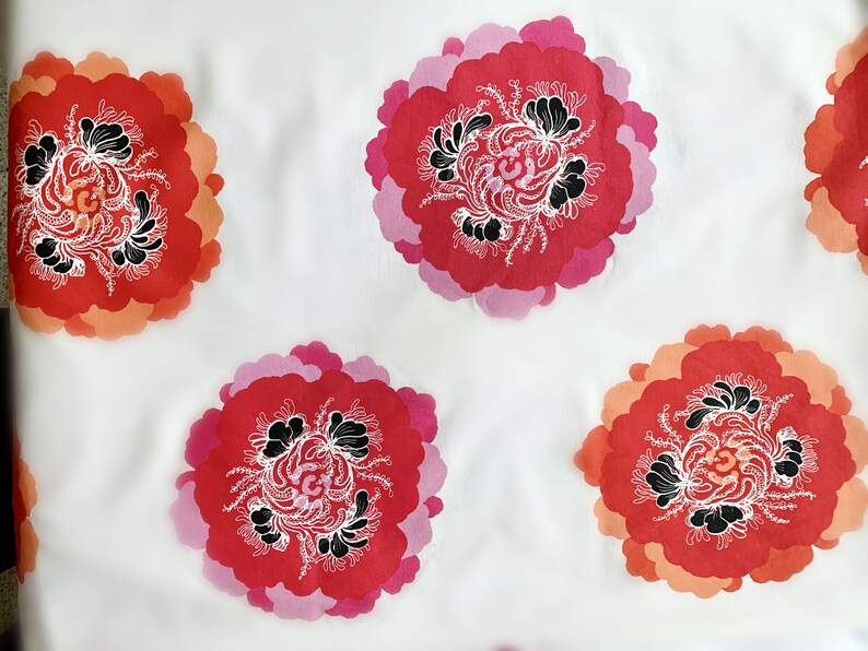 May include: White fabric with a repeating pattern of pink, red, and orange stylized flowers with black and white details.