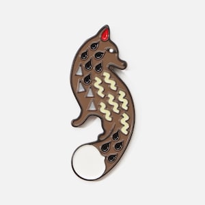 Könnte beinhalten: Eine braune Emaille-Anstecknadel in Form eines stilisierten Fuchses mit einem weißen Schwanz, schwarzen Augen und einer roten Nase. Der Fuchs hat ein Muster aus weißen Zickzacklinien und schwarzen Tropfenformen auf seinem Körper.