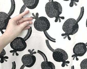 May include: White fabric with a repeating pattern of black and white polka dot shapes. The shapes are stylized and resemble a fruit or flower with a stem.