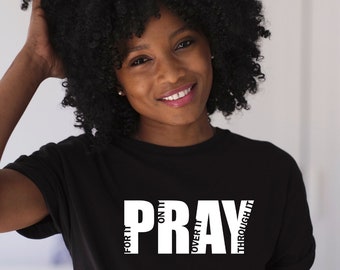 May include: Black t-shirt with white text that reads "PRAY" with the words "FOR THE", "ONLY", "OVER IT", and "THROUGH IT" written vertically around the word "PRAY".
