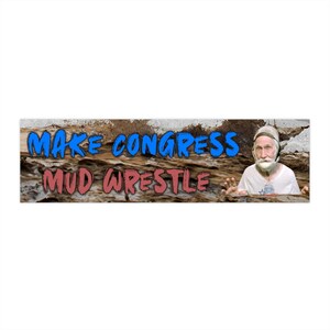 May include: A rectangular banner with the text "MAKE CONGRESS MUD WRESTLE" in blue and red, set against a textured brown background. A man with a white beard and a helmet is on the right side of the banner.