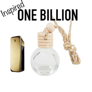 May include: A gold-coloured perfume bottle and a clear glass air freshener with a wooden top and a decorative rope. The text "Inspired ONE BILLION" is written in black on a white background.