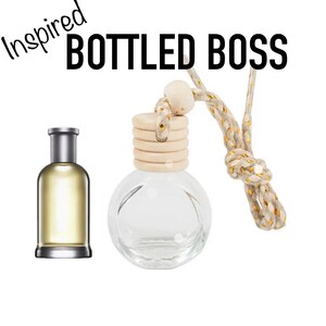 May include: Two glass bottles, one rectangular and one round, with silver caps. The rectangular bottle contains a yellow liquid. The round bottle has a wooden top and a decorative rope. Text reads "Inspired BOTTLED BOSS".