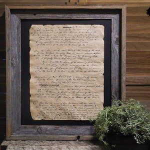 May include: A framed black and white print of a handwritten poem about the land of the free and the home of the brave. The poem is written in a cursive script and is framed in a rustic wooden frame.