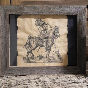 May include: A black and white print of a knight on horseback, framed in a rustic wooden frame. The knight is wearing armor and holding a sword. The horse is rearing up on its hind legs.