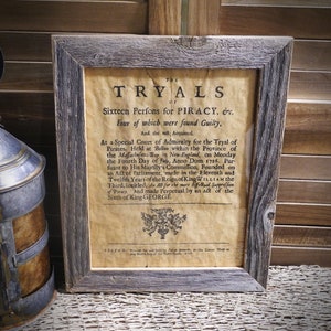 May include: A framed document with the title "THE TRYALS OF Sixteen Perfons for PIRACY, &c."  The document describes a court of admiralty held in Boston, Massachusetts in 1725 to try pirates.  Four of the sixteen people were found guilty, and the rest were acquitted.