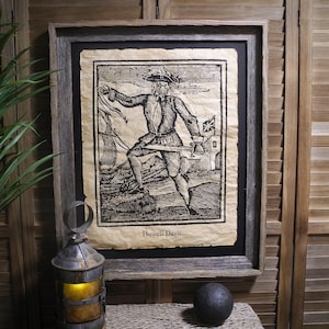 May include: A framed black and white woodcut print of a pirate holding a sword. The print is on aged paper and has the text "Howell Davis" at the bottom.