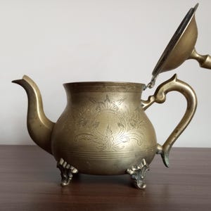 ハンドル付きのヴィンテージ真鍮製ティーポット。ヴィンテージの花のモチーフが刻まれた真鍮製のケトル。